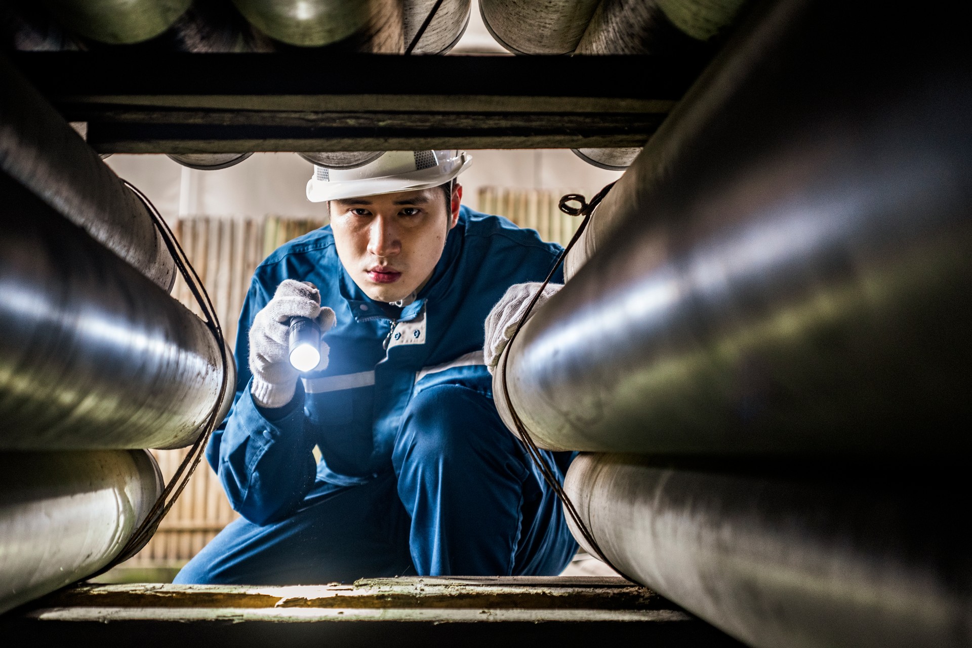 Col bleu effectuant l’inspection de tuyaux à la lumière d’une torche